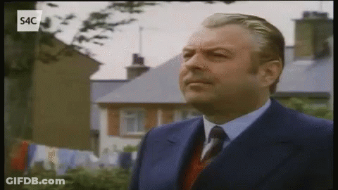 Man In Suit And Tie In Front Of Houses GIF