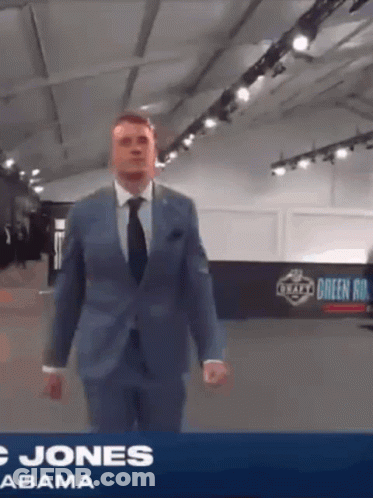 Man In Suit And Tie In Front Of Jones Abama Banner GIF
