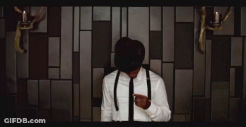 Man In Suit And Tie In Front Of Light Bulb Wall GIF