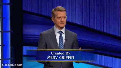 Man In Suit And Tie In Front Of Merv Griffin Sign GIF
