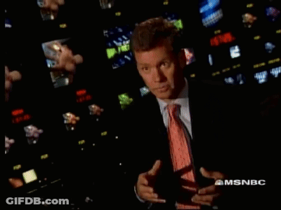 Man In Suit And Tie In Front Of MSNBC Screens GIF