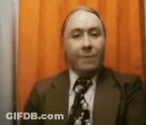Man In Suit And Tie In Front Of Orange Curtain GIF