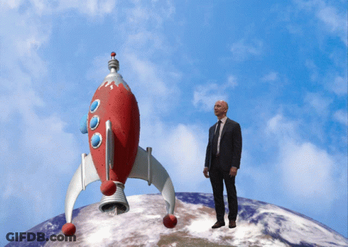 Man In Suit And Tie In Front Of Red Rocket GIF