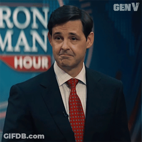 Man In Suit And Tie In Front Of Ron Man Hour Sign GIF