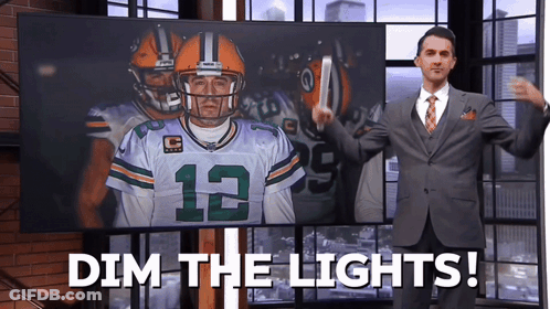 Man In Suit And Tie In Front Of Screen Saying Dim The Lights GIF