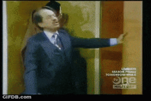 Man In Suit And Tie In Front Of TV Wall GIF