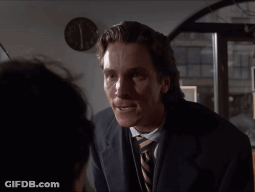 Man In Suit And Tie In Front Of Wall Clock Showing Almost 5:00 GIF