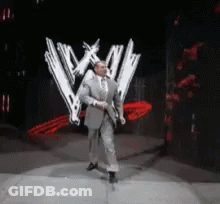 Man In Suit And Tie In Front Of WWE Logo GIF