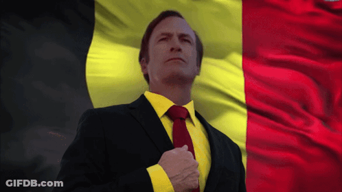 Man In Suit And Tie In Front Of Yellow And Red Flag GIF