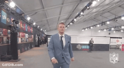 Man In Suit And Tie In Room With NFL Logo GIF
