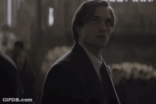 Man In Suit And Tie Looking At Camera In Dark Room GIF