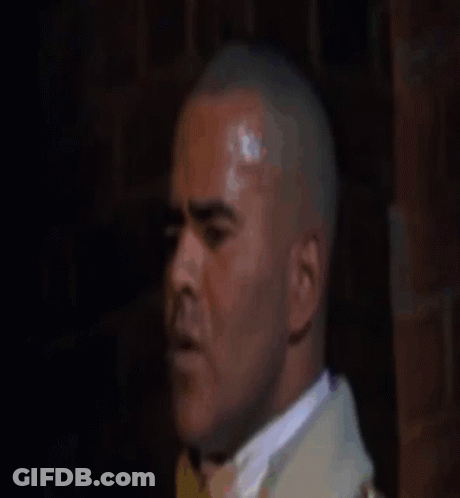 Man In Suit And Tie Looking At Camera In Dark Room GIF