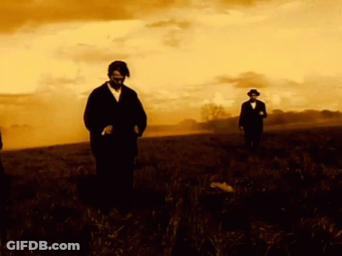 Man In Suit And Tie Looks At Camera In Dark GIF