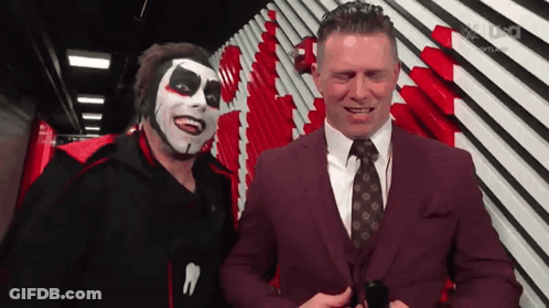 Man In Suit And Tie Next To Clown Mask GIF