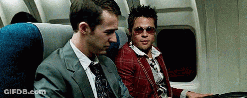 Man In Suit And Tie Next To Man In Sunglasses On Plane GIF