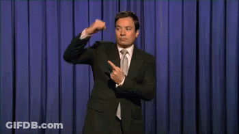 Man In Suit And Tie On Stage With Blue Curtain GIF