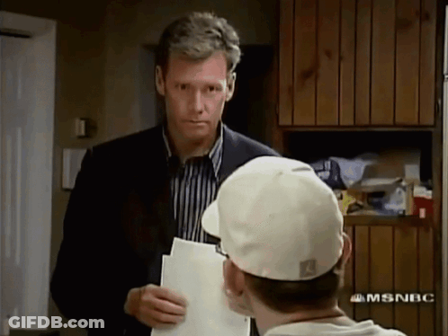 Man In Suit And Tie Saying Have A Seat GIF