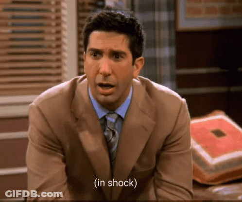 Man In Suit And Tie Shocked On Couch GIF