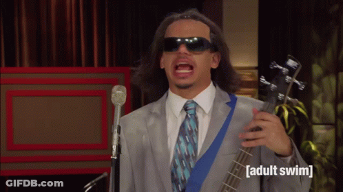 Man In Suit And Tie Singing Into Microphone Holding Adult Swim Guitar GIF