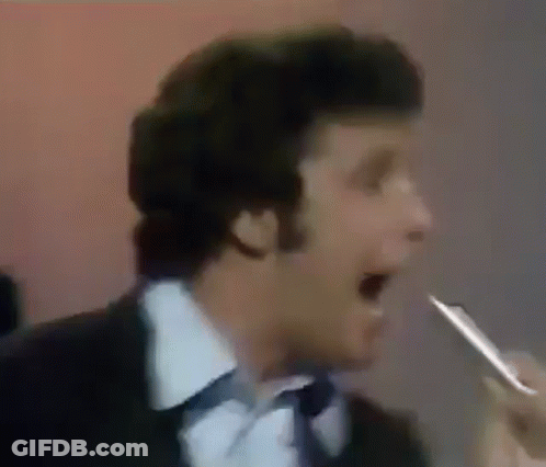 Man In Suit And Tie Singing Into Microphone Holding Pen GIF