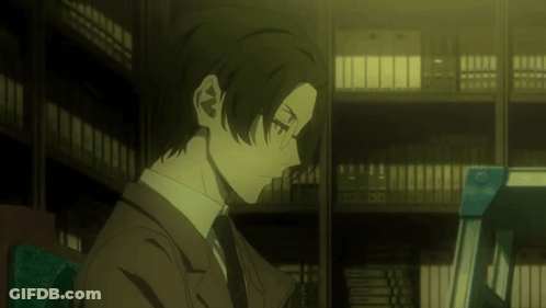 Man In Suit And Tie Sits In Library GIF
