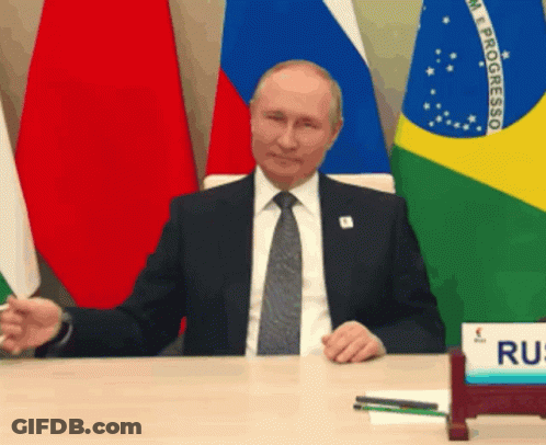 Man In Suit And Tie Sitting At Desk With Progresso Flags GIF