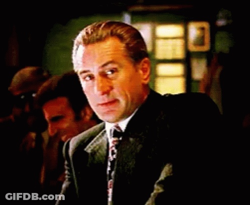 Man In Suit And Tie Sitting At Table Looking At Camera GIF