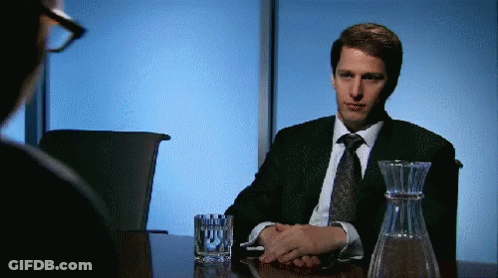 Man In Suit And Tie Sitting At Table With Glass Of Water And Decanter GIF
