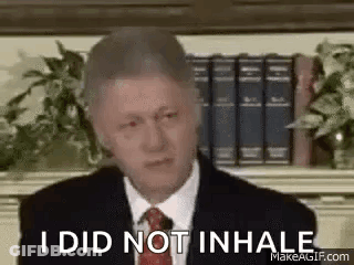 Man In Suit And Tie Sitting Before Bookshelf GIF