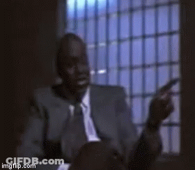 Man In Suit And Tie Sitting By Barred Window GIF