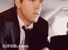 Man In Suit And Tie Sitting In Airplane GIF