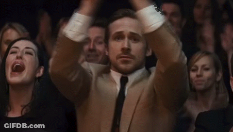 Man In Suit And Tie Sitting In Crowd GIF