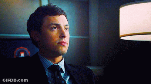 Man In Suit And Tie Sitting In Dark Room GIF