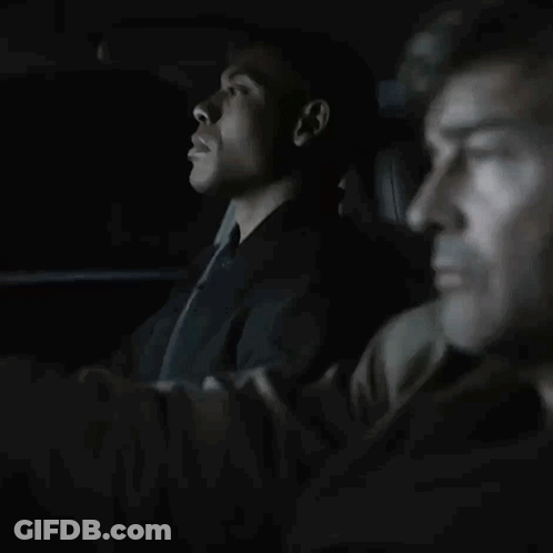 Man In Suit And Tie Sitting In Dark Room GIF