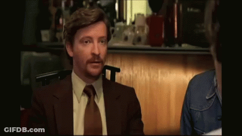 Man In Suit And Tie Sitting In Dark Room GIF