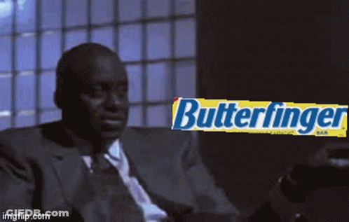 Man In Suit And Tie Sitting In Front Of Butterfinger Bar GIF