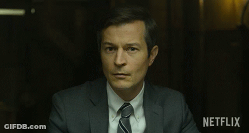 Man In Suit And Tie Sitting In Front Of Netflix Sign GIF