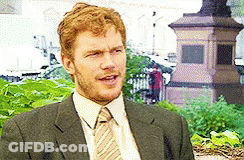 Man In Suit And Tie Sitting In Front Of Statue GIF