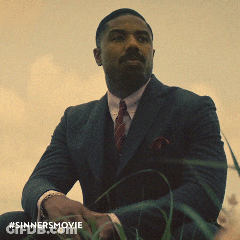 Man In Suit And Tie Sitting In Grass With #Sinnersmovie GIF