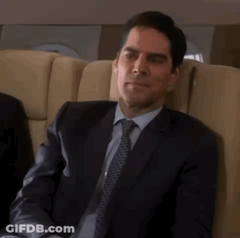 Man In Suit And Tie Sitting In Plane Chair GIF