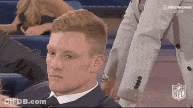 Man In Suit And Tie Sitting In Stadium With NFL Logo GIF