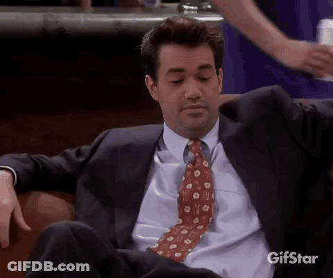Man In Suit And Tie Sitting On Couch Looking At Camera GIF