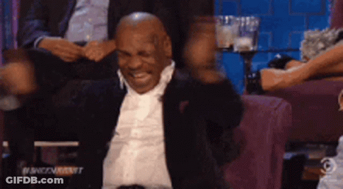 Man In Suit And Tie Sitting With Arms Out GIF