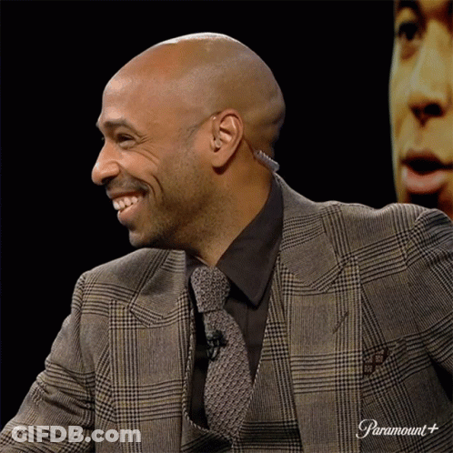 Man In Suit And Tie Smiling At Paramount Sign GIF