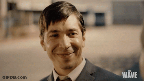 Man In Suit And Tie Smiling At The Wave Sign GIF