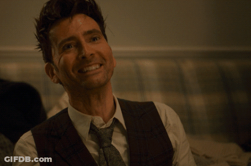 Man In Suit And Tie Smiling At Yellow Brilliant Sign GIF