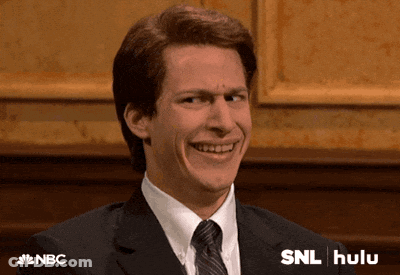 Man In Suit And Tie Smiling Beside SNL Hulu Sign GIF