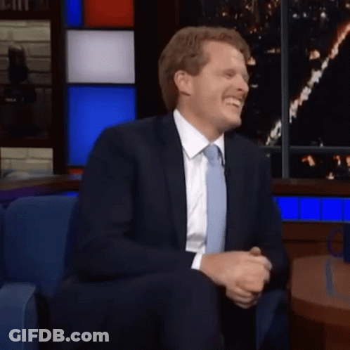 Man In Suit And Tie Smiling In Chair GIF