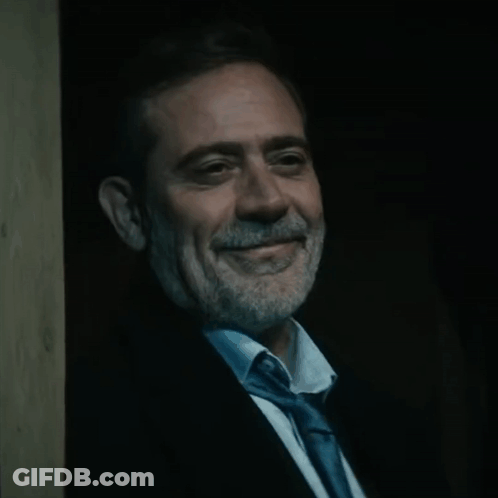 Man In Suit And Tie Smiling In Dark GIF