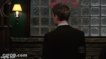 Man In Suit And Tie Smiling In Front Of Brick Wall GIF